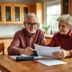 Couple engaged in retirement planning with financial documents at kitchen table