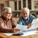 Senior couple engaged in retirement planning with financial documents at kitchen table