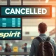 A passenger looks at a canceled Spirit Airlines flight on a departure board, illustrating the widespread Spirit Airlines cancellations impacting travelers.
