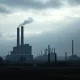 An image depicting the urgent crisis facing the UK bioethanol industry, with a struggling industrial plant under a cloudy sky.