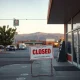 A closed grocery store entrance with a 'For Lease' sign, symbolizing the devastating impact of US tariffs on a California grocer.