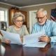 Elderly couple discussing Social Security taxes elimination proposal with financial documents