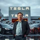 Elon Musk Tesla pay package announcement with futuristic technology backdrop
