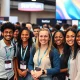 Volunteers helping attendees at StockPil Disrupt 2025 tech conference with startup exhibits in background