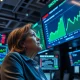 Cathie Wood analyzes energy stock investment data on a trading floor display.
